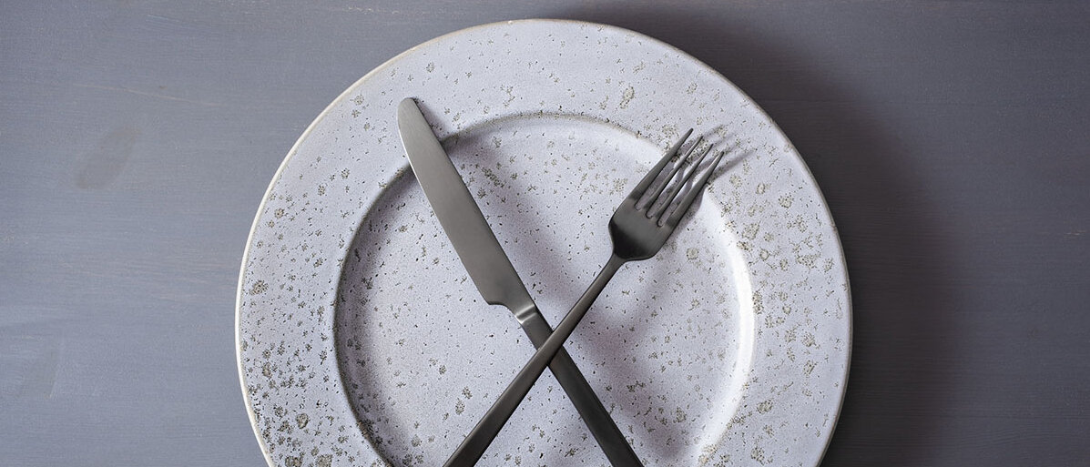 Ein leerer Teller, auf dem Messer und Gabel überkreuzt liegen.