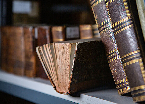Alte Bücher mit vergilbten Seiten und Ledereinbänden in einem Regal